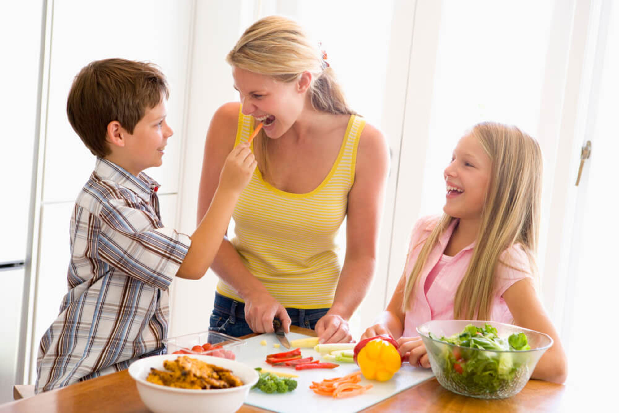 Mãe e dois filhos felizes ao redor da mesa, a mãe segue dicas para cuidar da saúde da família.