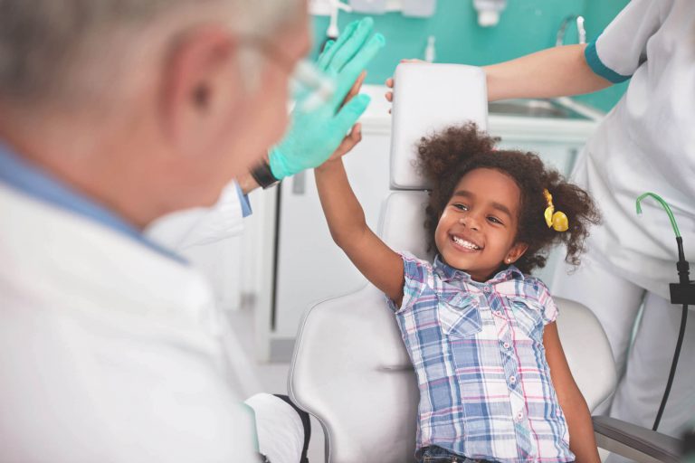 Criança rindo para médico sem medo de ir a uma consulta médica ou dentista.