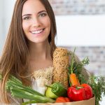 Mulher com cesta de alimentos e feliz por consegui-los digerir adequadamente devido ao uso dos probióticos.