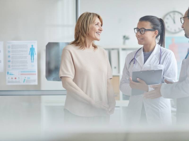Mulher conversando com duas médicas.