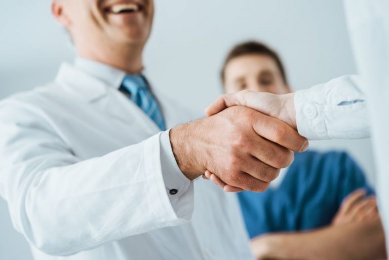 Médicos se cumprimentando e paciente observando. Uma das vantagens de escolher a melhor clínica médica.