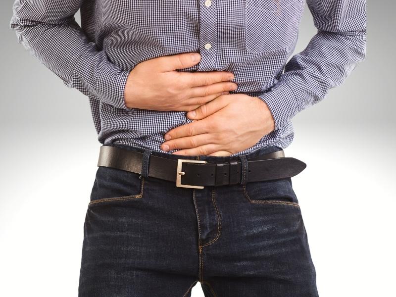 Homem com as mãos na barriga com dor.