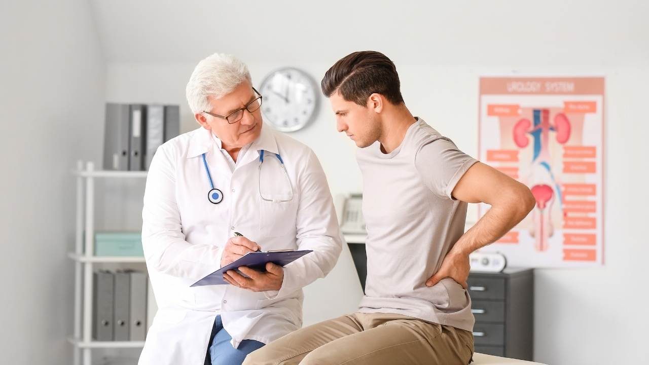 Médico urologista realizando atendimento com paciente homem.