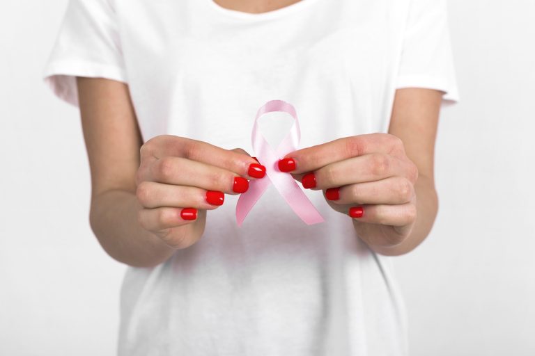 Mulher segurando laço rosa simbolo da luta contra o câncer de mama.