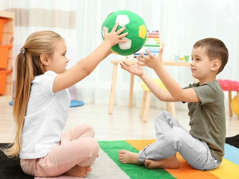 Menina e menino brincando com bola.