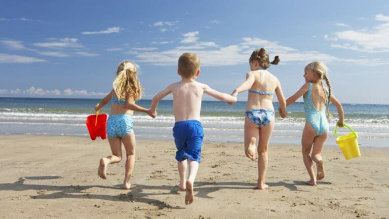 Crianças correndo e brincando na praia.