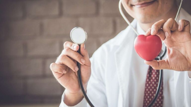 Médico segurando coração e estetoscópio simbolizando a prevenção do infarto.