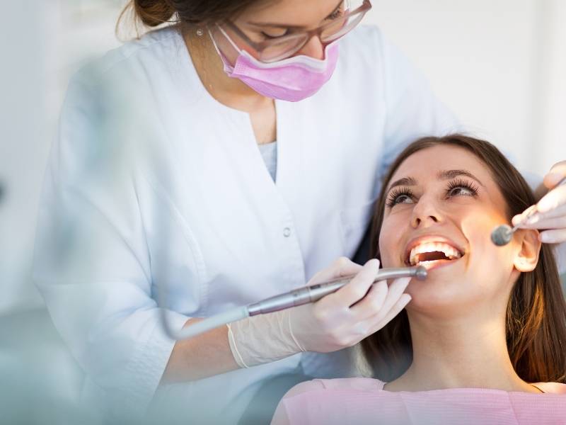 Médica dentista examinando a saúde bucal de mulher.