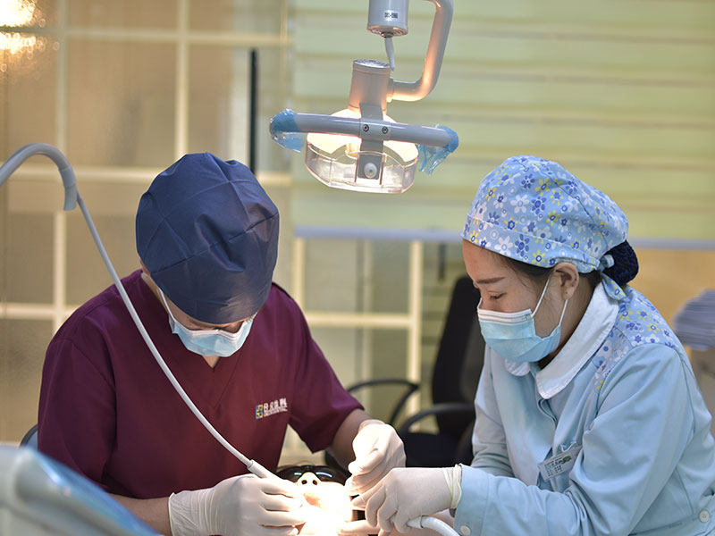 Dentistas realizando restauração dentária em paciente.