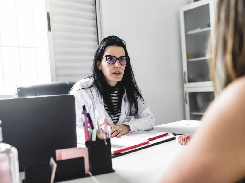 Médica dermatologista fazendo anamnese com paciente.