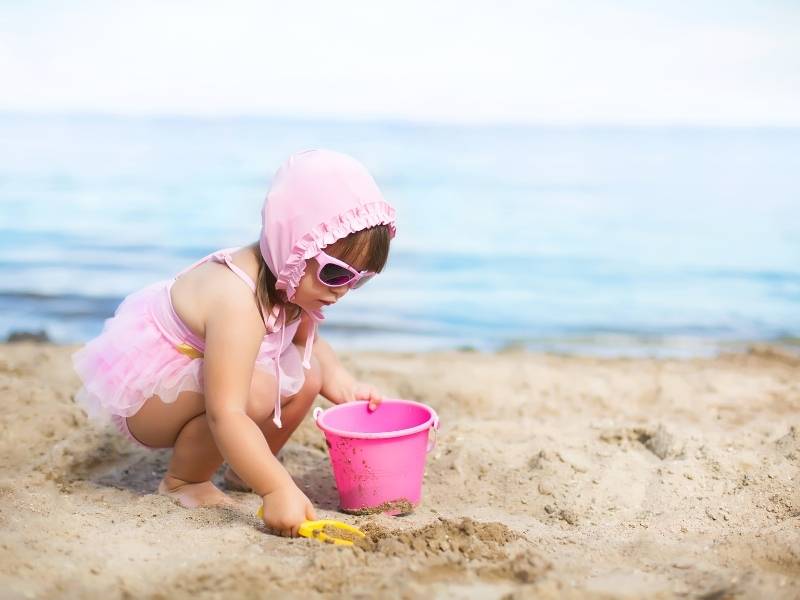 Criança do sexo feminino brincando na areia.