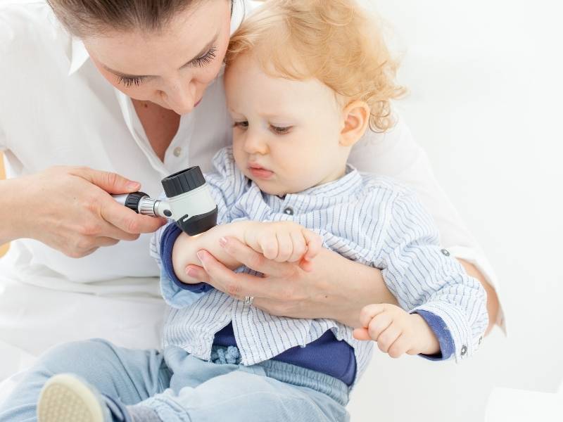 Médica dermatologista analisando pele de bebê.