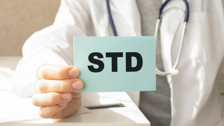 Médico segurando placa com a sigla DST.