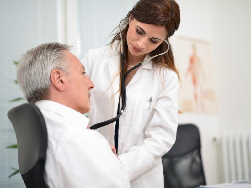 Médica cardiologista fazendo atendimento de paciente homem.