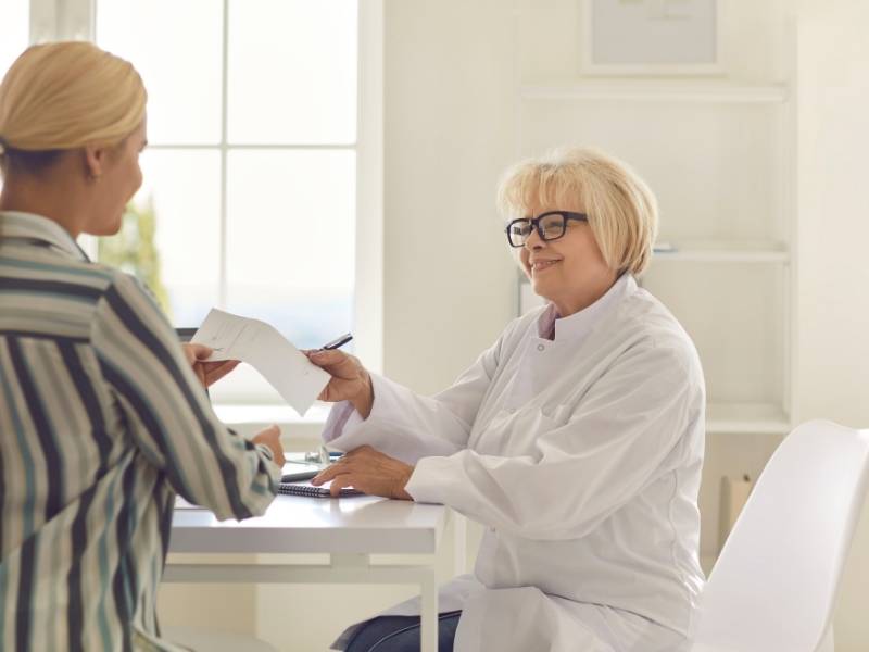 Médica mulher e paciente mulher conversando no consultório.