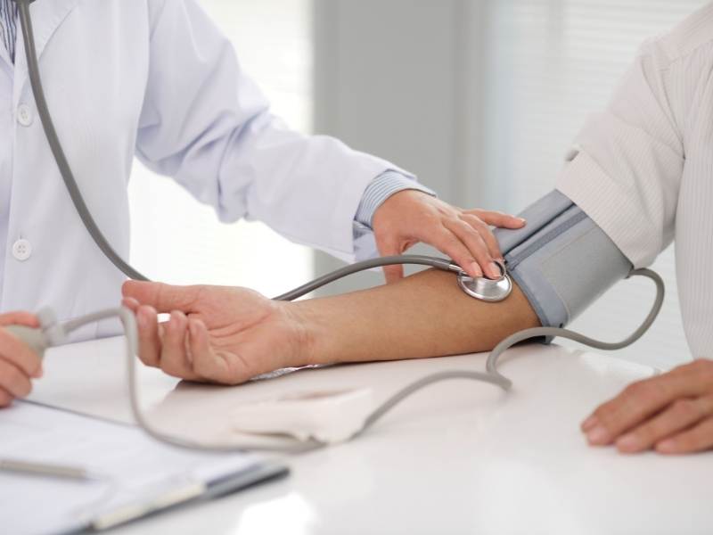 Médico medindo pressão arterial de paciente.