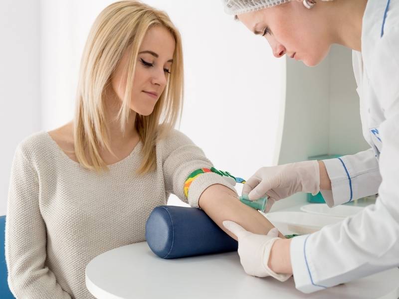 Mulher realizando exame de sangue para analisar possibilidade de câncer de mama.