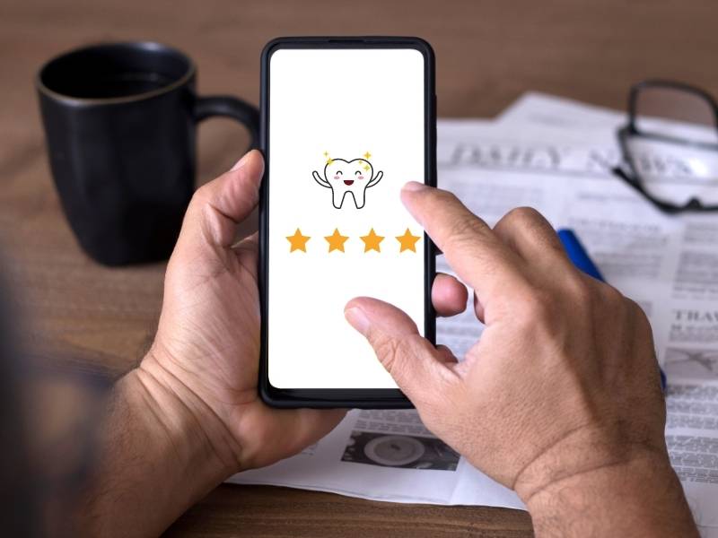 Homem usando celular para ver avaliações de dentistas.