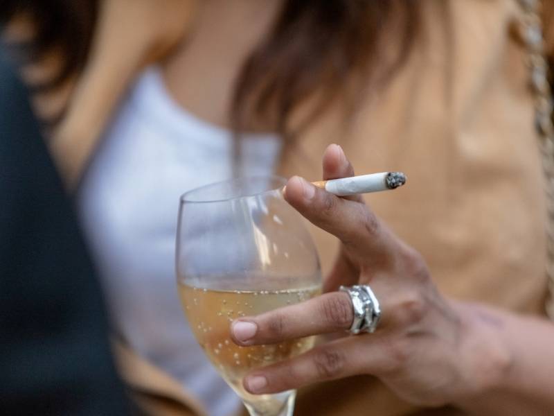 Mulher bebendo e fumando aumentando o risco do desenvolvimento de câncer de mama.