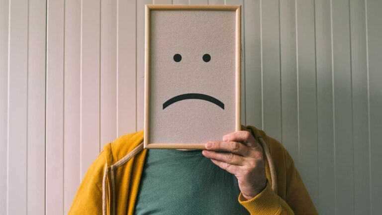 Imagem ilustrativa de pessoa com quadro a frente do rosto simbolizando tristeza e depressão.