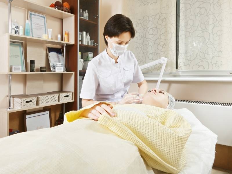 Médica dermatologista realizando aplicação de injeção de plasma em paciente.