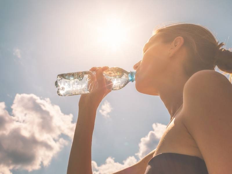 Mulher jovem bebendo agua em garrafa.