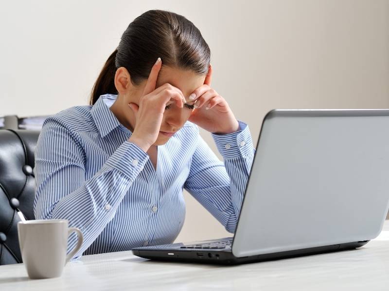 Mulher jovem sentada em frente ao computador desanimada.