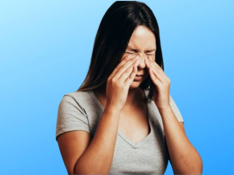 Mulher jovem realizando massagem nasal.