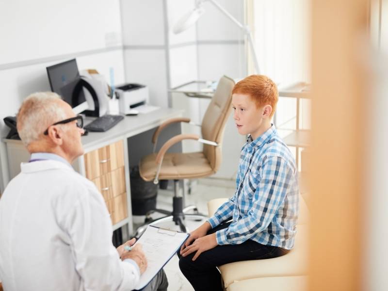 Médico realizando anamnese com paciente criança.