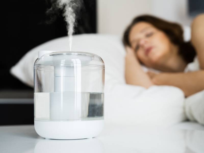 Mulher dormindo com humidificador de ar ligado.