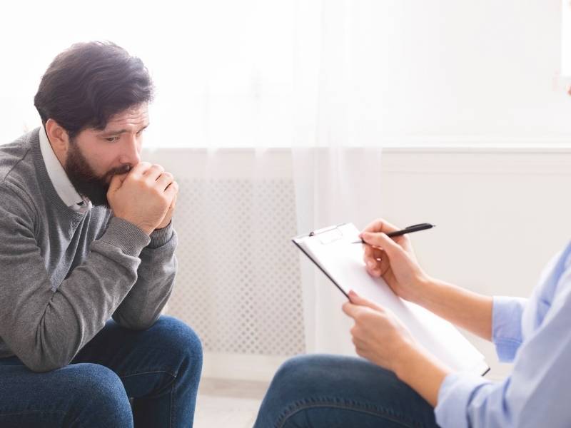 Homem jovem sentado conversando com especialista em ansiedade.