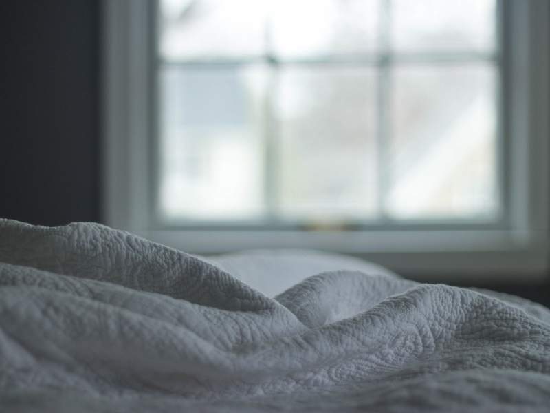 Imagem de cama bagunçada durante o dia.