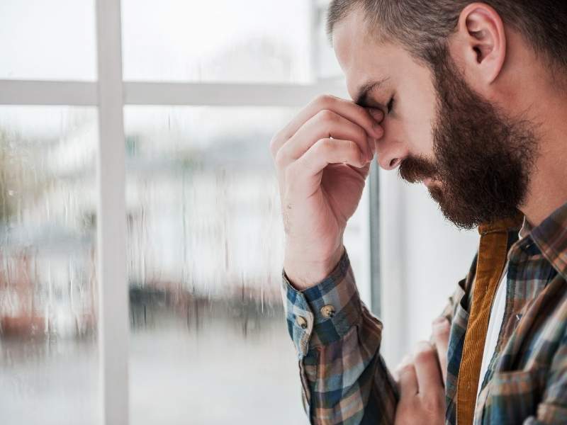Homem com feição triste com a mão no rosto.