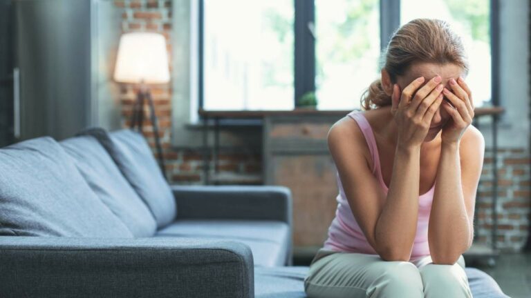 Mulher jovem sentada sendo afetada pelos sintomas da depressão.
