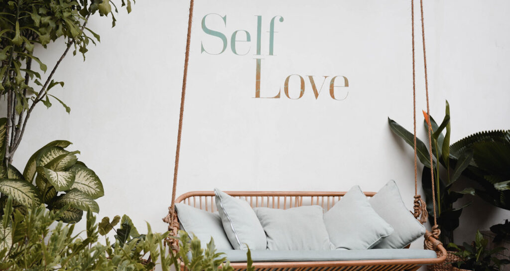 jardim com as palavras self love, ou autocompaixão, escritas na parede