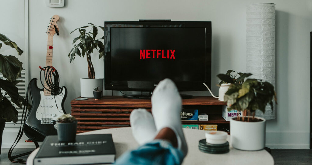 pessoa relaxando e assistindo netflix na televisão para relaxar a mente