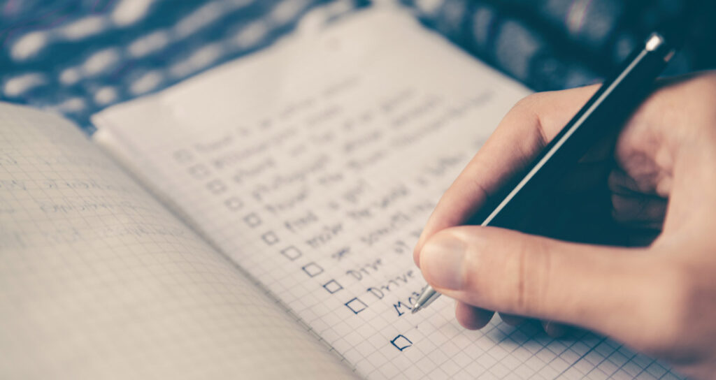 pessoa organizando sua rotina ao escrever suas atividades em um caderno