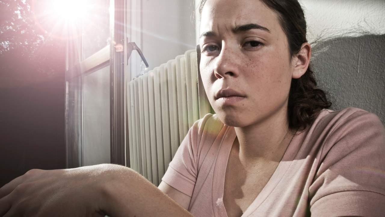 Mulher sentada com feição triste.