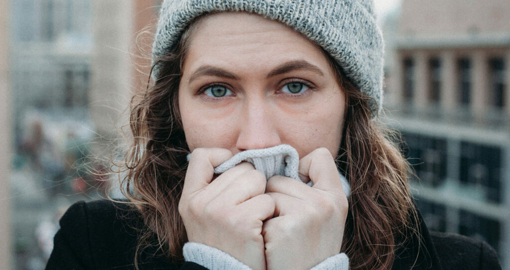 mulher agasalhada, com frio e tendo calafrios, um dos sintomas da ansiedade