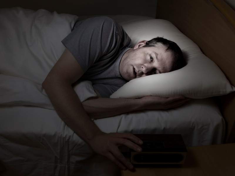Homem sonolento deitado na cama.