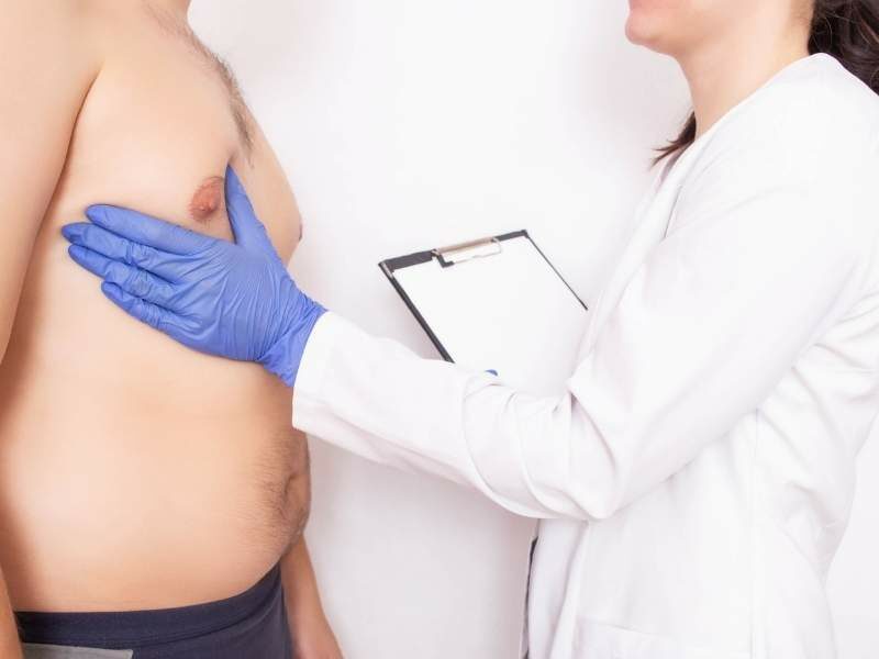 Médica examinando possível câncer de mama masculino. 