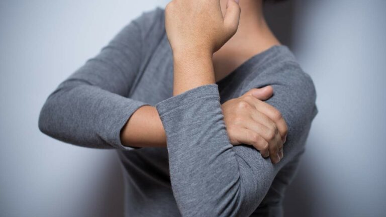 Mulher com dor no braço em razão de possível câncer de mama.