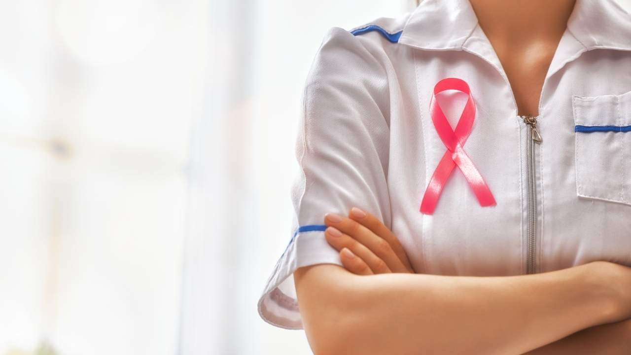 Médica com laço do outubro rosa na camisa.