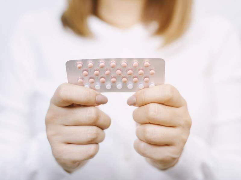Mulher segurando remédios para tratamento a base de hormonioterapia.