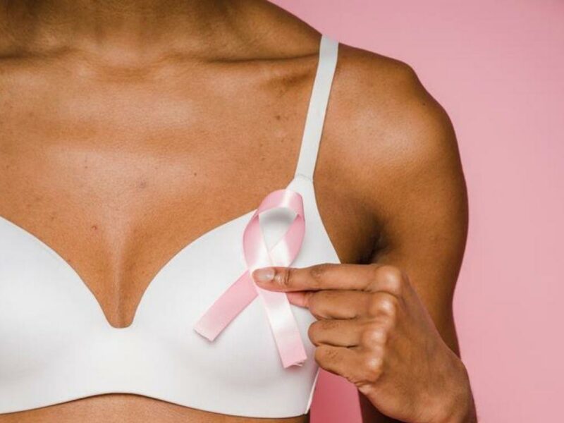 Mulher segurando laço cor de rosa símbolo do outubro rosa e do combate ao câncer de mama.