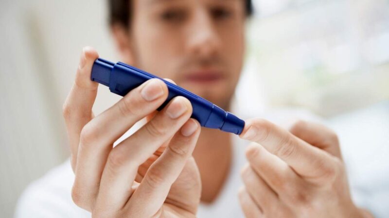 Homem jovem com diabetes lada aferindo glicemia.