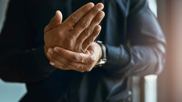 Homem sentado em cadeira com formigamento nas mãos.