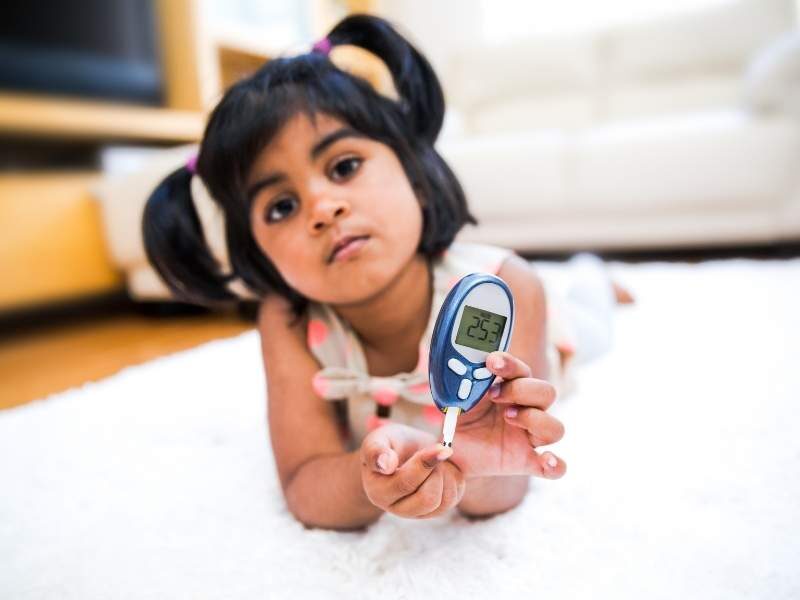 Criança segurando medidor de diabetes.