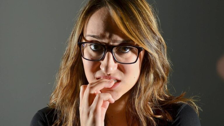 Mulher ansiosa roendo as unhas da mão.