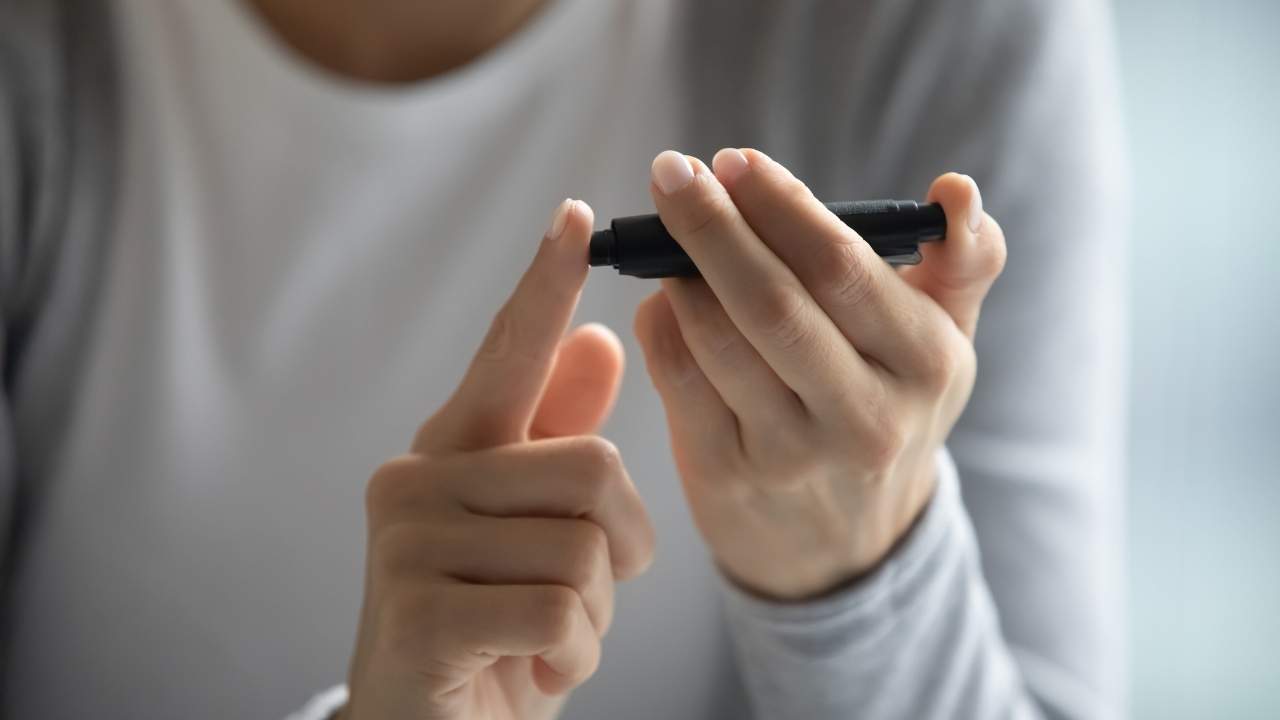 Mulher jovem aferindo níveis de glicemia para ver diabetes.